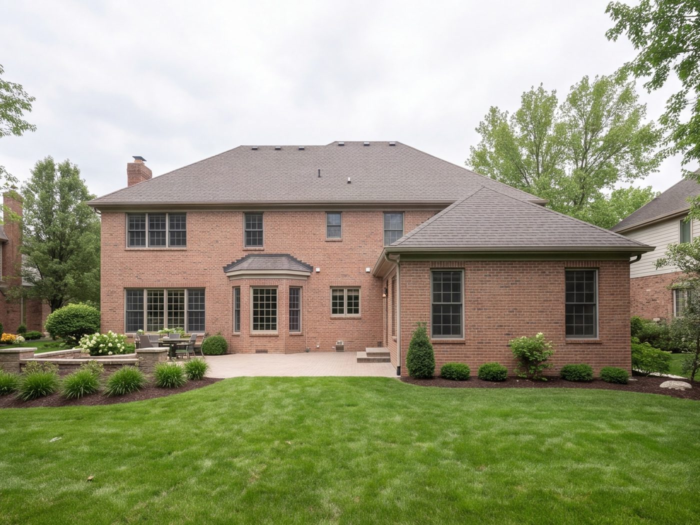 Back of a brick house with a new addition matching the original walls and roofline